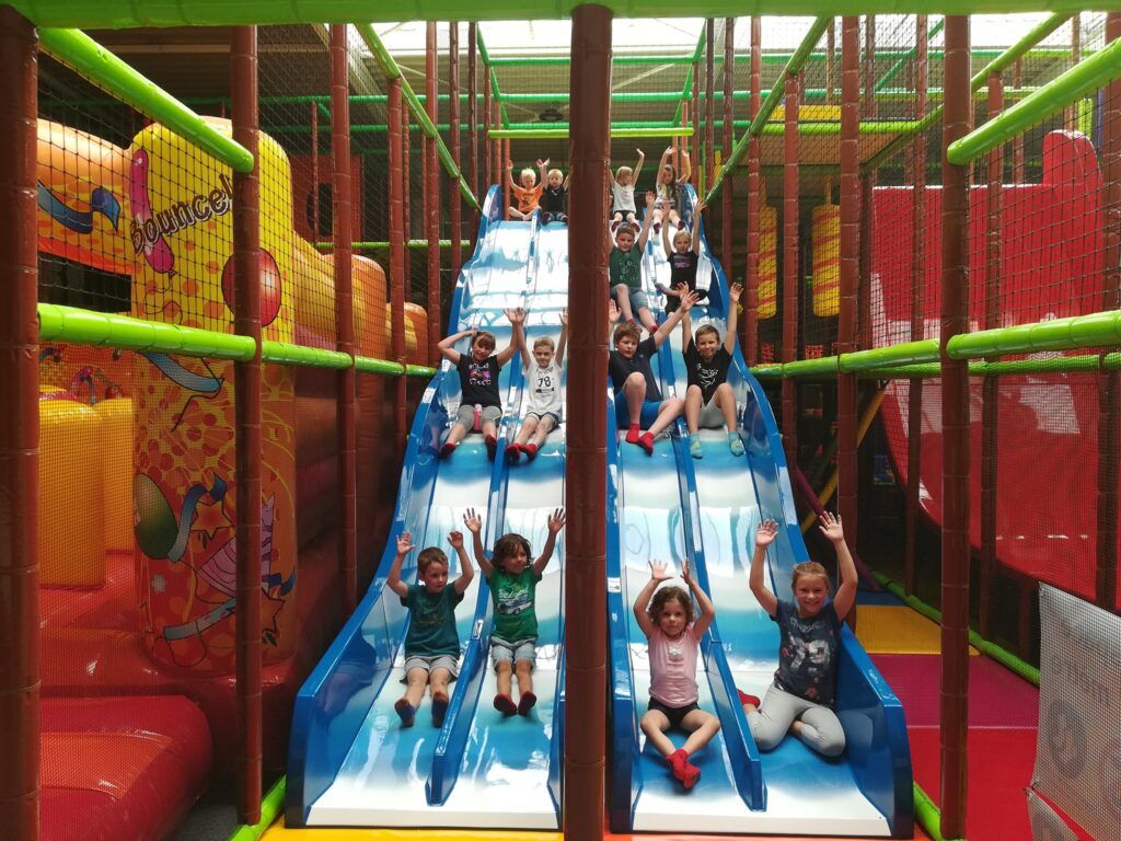 Niños bajando por un tobogán triple en un parque de bolas